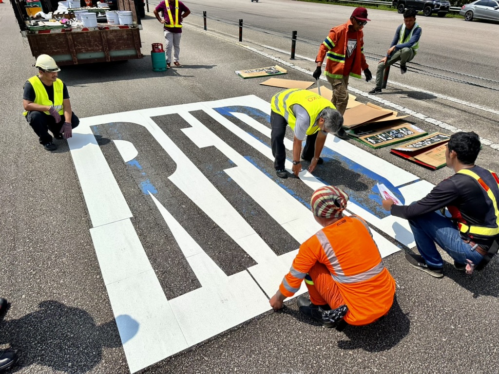 Crew applying preformed thermoplastic crossing markings using heat torches