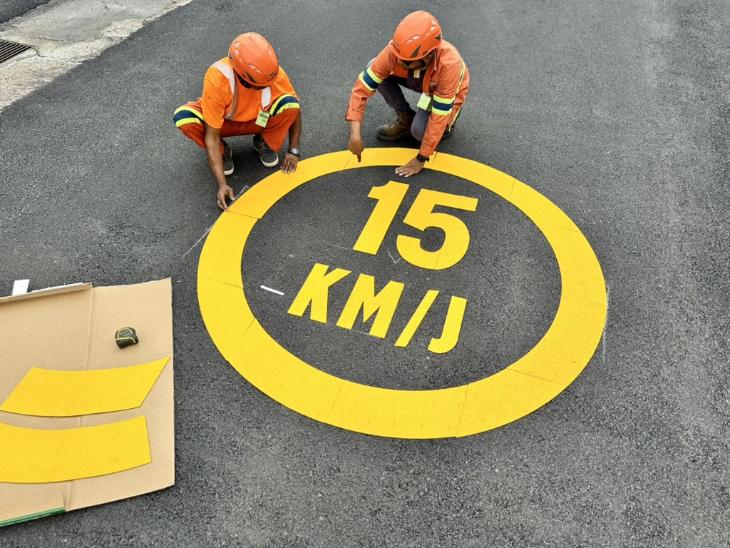 Workers arranging a yellow 15 KM/J preformed thermoplastic speed roundel